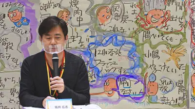 ご本人の体験を描いたグラフィックを前にして語る、小腸がん経験者の坂井さん